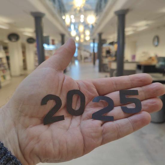 Håndflade med udklippede tal i papir: 2025.